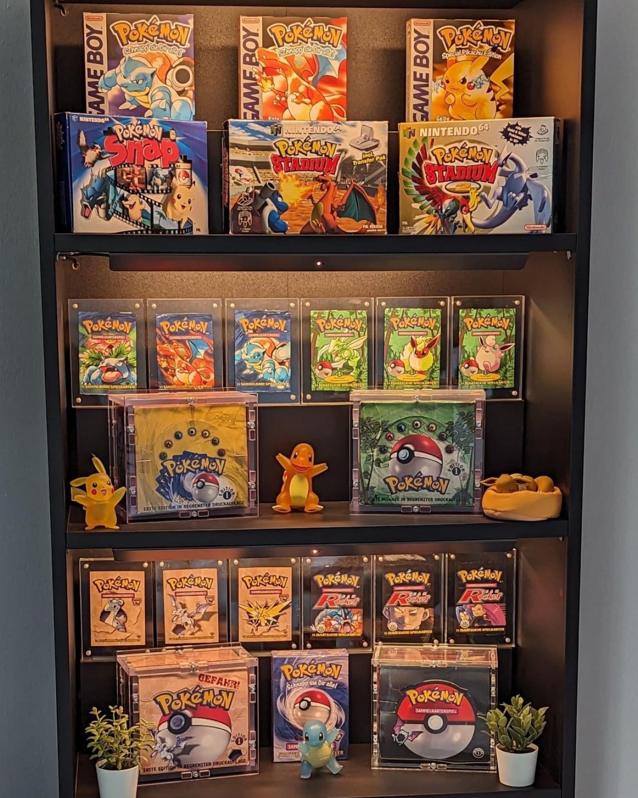 Estante iluminada com coleção de boosters, caixas e bonecos de Pokémon